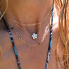 Woman wearing an Adelaide Mini necklace, Greenwich Flower necklace, and personalized Classic 6 Birthstone necklace.