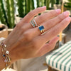 Woman's hand wearing three Rosecliff Stackable rings & a Warren ring featuring a 10 x 8mm Atlantic Blue Topaz center stone.