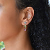 Close-up of woman's ear wearing a personalized Grand 3 Birthstone earring featuring aquamarine, peridot, and pink sapphire.