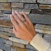 Hand wearing a Greenwich ring featuring two 4 mm faceted round cut gemstones and one 2.1 mm diamond prong set in 14k gold