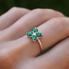 A hand showcasing the 4 Emerald Diamond Greenwich Ring by HAVERHILL, featuring four vibrant emeralds surrounding a sparkling diamond, epitomizing timeless love and devotion.