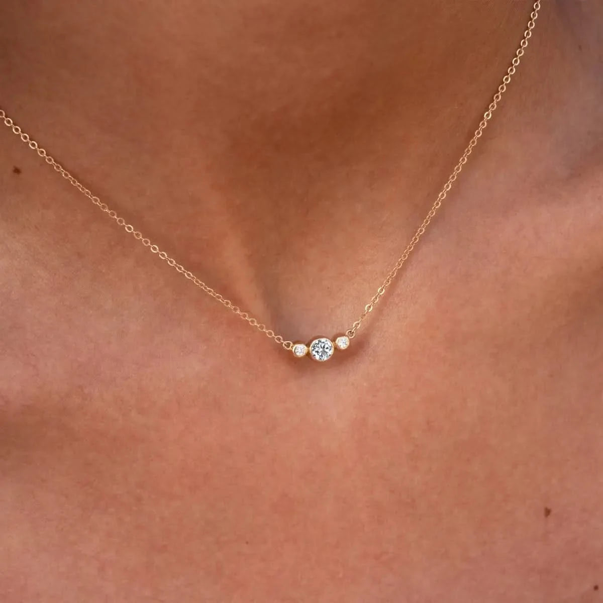 Close-up of Barrington 3 Stone Necklace featuring a 4 mm round cut Diamond center stone framed by two 2 mm round cut Diamonds bezel set in 14k yellow gold on a saffron chain – front view.