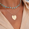 Woman wearing a Newport Grand Turquoise necklace and a Large Flat Heart pendant engraved with A + H on an Adelaide chain.