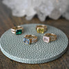 Four Warren Horizontal Birthstone rings, two with accent stones, all featuring an 8x10mm emerald cut, bezel set center stone.