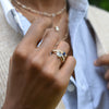 Woman's hand wearing three rings stacked on one finger including a Rosecliff ring, Grand ring, and Greenwich Solitaire ring.