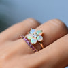Close-up of woman's finger wearing a Greenwich Flower Opal & Diamond ring and Rosecliff Pink Sapphire Stackable ring.