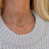 Woman wearing a Rosecliff Bar necklace featuring eleven 2mm prong set gemstones and a Bayberry 11 Birthstone Necklace.