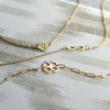 Flat lay of the Venus necklace, Infinity necklace, and Clover Adelaide Mini necklace, all in 14k yellow gold.