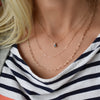 A woman wearing a Greenwich Solitaire Alexandrite & Diamond necklace, an Adelaide Mini necklace, and an Adelaide necklace.