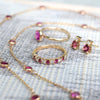Assorted pink sapphire jewelry including a Grand ring, Greenwich Solitaire earrings, Bayberry necklace, and Rosecliff ring.