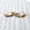 Rosecliff huggie earrings in 14k yellow gold featuring nine 2mm faceted round cut rainbow patterned gemstones.