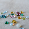 A scattered assortment of various gemstones of different shapes, sizes, and colors.