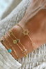 Wrist wearing multiple personalized bracelets including a Bayberry White Topaz Star of David bracelet in 14k yellow gold.