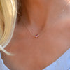 Blonde woman wearing a Grand Pink Sapphire necklace in 14k yellow gold featuring one 6mm briolette cut, bezel set gemstone.