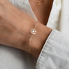 Close-up of a woman's wrist wearing a 14k yellow gold Clover Adelaide Mini bracelet featuring a 9.1mm clover cutout.