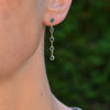 Close-up of a woman's ear wearing a Classic 5 Birthstone drop earring featuring 4mm briolette cut, bezel set emeralds.