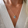 Close-up of a woman wearing a personalized Classic 4 birthstone necklace and a Warren pendant on an Adelaide Mini chain.