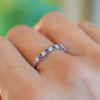 A woman wearing a Rosecliff Stackable ring in 14k white gold featuring eleven alternating 2mm faceted diamonds and amethysts.