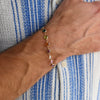 Man's wrist wearing a Rainbow Grand Newport bracelet featuring 6mm briolette cut, bezel set gemstones in a rainbow pattern.