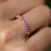 Close-up of a finger wearing a Rosecliff Pink Sapphire Stackable ring featuring eleven 2mm prong set gemstones.