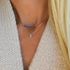 Blonde woman wearing a 14k yellow gold Rosecliff Sapphire Bar necklace and Greenwich Solitaire Nantucket Blue Topaz necklace.
