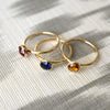 Grand Citrine, Grand Garnet, and Sapphire rings in 14k gold, each featuring a 6mm round briolette-cut gemstone, displayed elegantly side by side.