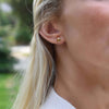 Woman wearing a 14k yellow gold Grand stud earring featuring one 6 mm briolette cut bezel set citrine.