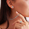 Woman wearing a 14k yellow gold Grand stud earrings each featuring one 6 mm briolette cut bezel set Turquoise.