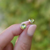 Woman showcasing a pair of 14k yellow gold Grand stud earrings each featuring one 6 mm briolette cut peridot