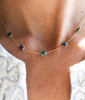 Woman wearing a Terra Grand 5 Stone necklace featuring alternating 6mm briolette cut, bezel set emerald & sapphire gemstones.