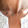 Close-up of a woman wearing a Terra Grand 5 Stone necklace featuring alternating 6mm emerald and sapphire gemstones.