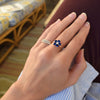 Woman wearing two rings including a Greenwich ring featuring five 4 mm sapphires and one 2.1 mm diamond prong set in 14k gold