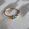 A Greenwich ring featuring one 4 mm Blue Topaz and one 2.1 mm Diamond prong set in 14k gold