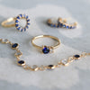 Jewelry including a Greenwich ring featuring one 4 mm faceted Solitaire Sapphire and one 2.1 mm diamond prong set in 14k gold