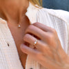 Woman wearing a Greenwich ring in 14k Yellow Gold featuring one 4 mm faceted round cut Solitaire Opal and one 2.1 mm diamond prong set