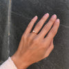Woman wearing a Greenwich ring featuring one 4 mm faceted round cut Solitaire Opal and one 2.1 mm diamond prong set in 14k gold