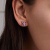 Woman showcasing a Greenwich Birthstone Earrings in 14k Gold featuring four 4 mm faceted round cut, prong set Pink Tourmalines and one 2.1 mm Diamond.