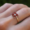 Woman wearing a Greenwich ring featuring four 4 mm faceted round cut garnets and one 2.1 mm diamond prong set in 14k gold