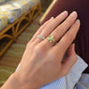 Woman wearing two rings including a Greenwich ring featuring five 4 mm peridots and one 2.1 mm diamond prong set in 14k gold