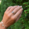 Woman wearing a Greenwich ring featuring four 4 mm faceted round Aquamarines and one 2.1 mm Diamond prong set in 14k gold.