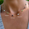 Woman wearing a personalized Grand 9 Birthstone necklace featuring 6mm bezel set stones on a 1.17mm cable chain.