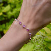 Wrist wearing a Newport Grand Pink Sapphire bracelet featuring a continuous strand of 6mm briolette cut, bezel set gemstones.