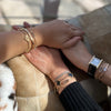 Three friends holding hands while each wearing a matching personalized Adelaide 3 Pavé Link bracelet in 14k yellow gold.