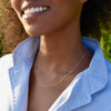 A woman wearing a personalized Classic 2 Birthstone asymmetrical necklace featuring 4mm briolette cut, bezel set gemstones.