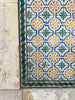 Close-up of ornate tiles on a building featuring blue, yellow, white, red, green, and black.
