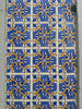 Close-up of ornate tiles on a building featuring blue, white, and yellow.