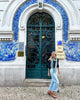 Haverhill Leach walks in front of the ornate, teal doors of Brandfire. White & blue decorative tiles adorn the archway.