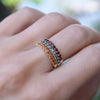 Stack of three Rosecliff rings worn on a finger featuring garnet, Nantucket blue topaz, and citrine, all in 14k yellow gold.