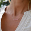Woman wearing a Rosecliff Pink Tourmaline Bar necklace featuring eleven 2mm prong set gemstones on a 1.17mm cable chain.
