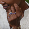 Woman wearing eight randomly stacked Rosecliff Stackable rings on her fingers, all featuring eleven 2mm prong set gemstones.